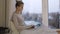 Beautiful woman typing on her laptop and sitting on windowsill