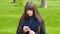 Beautiful woman uses cell smartphone outdoors in the park - detail . Young attractive happy girl relaxes in a city par