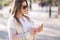 Beautiful woman using phone and drinks lemonade outdoor. Young blogger spend time in park