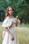 Beautiful woman in vintage dress beige. Cute girl in long dress walking in a pine forest. The style of the Queen.