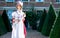 Beautiful woman in vintage Georgian dress and bonnet standing in garden of stately home