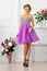 Beautiful woman in violet dress in luxury studio.