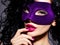 Beautiful woman in violet theatre mask on face and purple nails