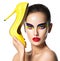 Beautiful woman with vivid make-up of eyes holds the yellow high heel