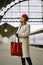 Beautiful woman is waiting for train on railway station. Girl travels light. Middle-aged female