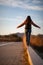 Beautiful woman walking and balancing on street curb or curbstone during sunset