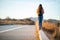 Beautiful woman walking and balancing on street curb or curbstone during sunset