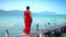 Beautiful woman walking down pier in long red dress. Phu Quoc Island. Landscape of mountains and sea. The woman walks on
