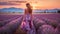 Beautiful woman walking in lavender field at sunset