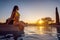 Beautiful woman watching the sunset sitting on swimming pool