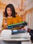 Beautiful woman wearing a brown blouse fixing a photocopier and smiling during maintenance using a screwdriver