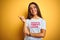 Beautiful woman wearing fanny t-shirt with irony comments over isolated yellow background with a big smile on face, pointing with