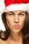 Beautiful woman wearing santas hat looking angry