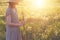 Beautiful woman wearing straw hat and long linen dress enjoying nature, holding bouquet of fresh beautiful wildflowers and green g