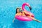 Beautiful woman, wearing swimsuit, lying on a pink flamingo air mattress in a pool of blue water, summer