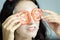 A beautiful woman wearing a towel and a white bathrobe has mask on face-covering eyes with sliced tomatoes with happy and relaxing