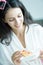 A beautiful woman wearing a towel and a white bathrobe has to eat a pizza with happy and relaxing on the bed at a condominium in