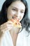 A beautiful woman wearing a towel and a white bathrobe has to eat a pizza with happy and relaxing on the bed at a condominium in