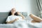 A beautiful woman wearing a towel and a white bathrobe and pink headband with happy and relaxing on the bed at a condominium in