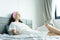 A beautiful woman wearing a towel and a white bathrobe and pink headband with happy and relaxing on the bed at a condominium in