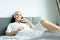 A beautiful woman wearing a towel and a white bathrobe and pink headband with happy and relaxing on the bed at a condominium in