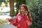 A beautiful woman wears a traditional Moroccan dress in red and embroidered in gold and silver. The beautiful woman is talking on