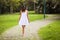 beautiful woman in a white dress, gracefully walking barefoot on a cobblestone path in a serene park