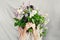 Beautiful woman in white dress hid her face behind large lilac bouquet