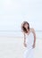 Beautiful woman in a white dress on the ocean coast. Happy girl on the beach, the wind fluttering hair.