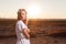 Beautiful woman in white dress posing on the sunset with look.