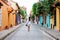 Beautiful woman on white dress walking alone at the colorful streets of the colonial walled city of Cartagena de Indias