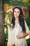 Beautiful woman in white posing in autumnal park. Young brunette woman spending time in autumn near a tree in forest