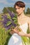 Beautiful woman in white sundress with a bouquet in the hands of lupine in field at sunset