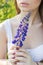 Beautiful woman in white sundress holding lupine flower in the hands