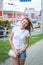 Beautiful woman in white t-shirt and denim shorts walks along the footpath in the city