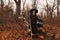 Beautiful woman in witches hat and costume holding broom near the cauldron in autumn forest. Halloween concept