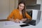 Beautiful woman working at home filling out and checking documents communicating through video conference