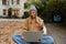 Beautiful woman working on laptop and drinking coffee while sitting in yard by sandbox