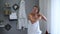 Beautiful woman wrapped in towel after shower is applying coconut oil her wet hair