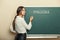 Beautiful woman writes on a blackboard the word impossible.