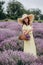 Beautiful woman in a yellow dress and hat with a basket of flowers in a field of fragrant lavender. Soft selective focus, art