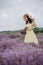 Beautiful woman in a yellow dress and hat with a basket of flowers in a field of fragrant lavender. Soft selective focus, art