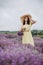 Beautiful woman in a yellow dress and hat with a basket of flowers in a field of fragrant lavender. Soft selective focus, art