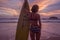 Beautiful woman with yellow surfboard on the beach over amazing sunset