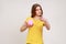 Beautiful woman of young age in yellow T-shirt investing in bitcoins, holding piggy bank and