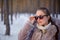 Beautiful womanin winter forest wearing a fur coat and sunglasses. It is snowing. She is happy in winter. Smiling