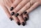 Beautiful womans hand with elegant manicure on marble background. Minimal black nail design