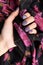 Beautiful womans hand with purple matte manicure holding fabric