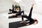 Beautiful women are doing Pilates in a bright studio. Three female athletes in black tracksuits doing exercises on yoga