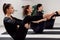 Beautiful women doing pilates in a bright studio. Three sportswomen in black sportswear do static exercises while